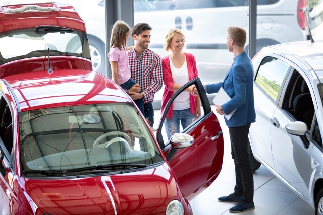 Car agent showing vehicle to young family